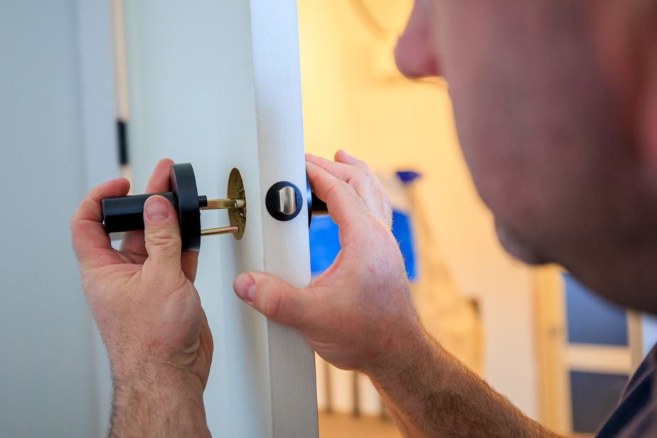 Un serrurier est en train d'installer des poignées de porte.